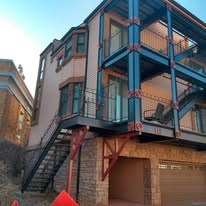 Multi-story home exterior with blue-teal painted framing and balconies